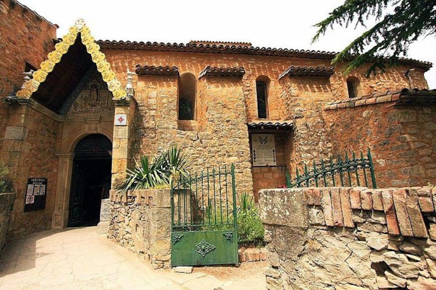 Un edificio de piedra con tejado de tejas, una puerta verde y un muro de piedra. 2
