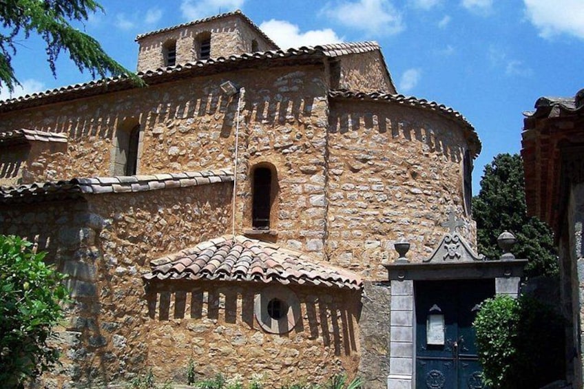 Un edificio de piedra con una torre de campanas, ventanas de arco y techo de tejas. 5