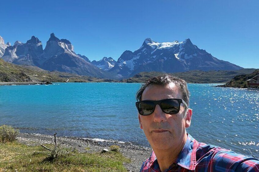 A man taking a selfie by a lake with mountains in the background. 1
