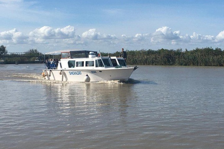 A boat named 'Sheraldo' on calm water with a forested shoreline in the background. 1