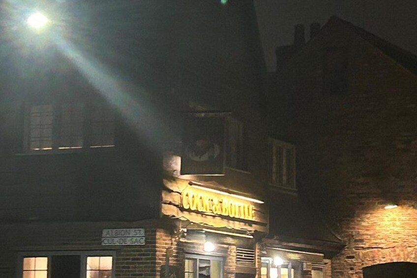 Un bâtiment avec une enseigne lumineuse, un panneau de signalisation et une façade en briques, de nuit. 5