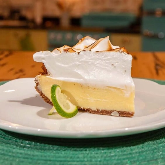 A slice of key lime pie with meringue on top, served on a white plate with a slice of lime on the side. 5