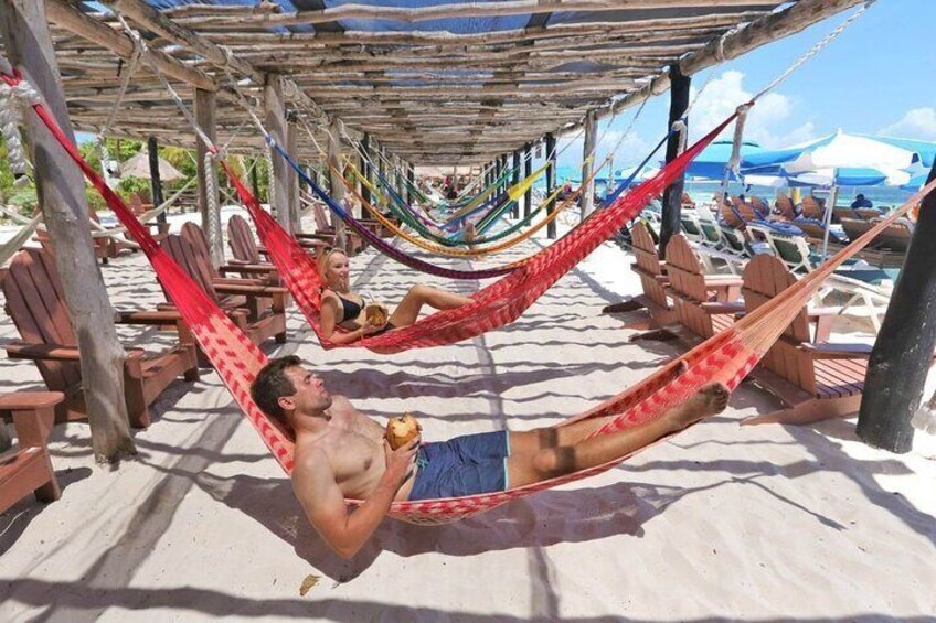 A beach scene with hammocks and lounge chairs under a wooden structure. 2