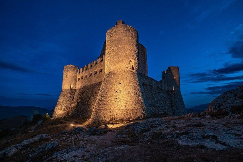 Eine mittelalterliche Burg im Zwielicht mit beleuchteten Mauern und einem Burggraben. 3