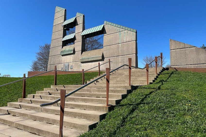 Un edificio in cemento dal design particolare, con una scalinata che vi conduce e una collina erbosa sullo sfondo. 1