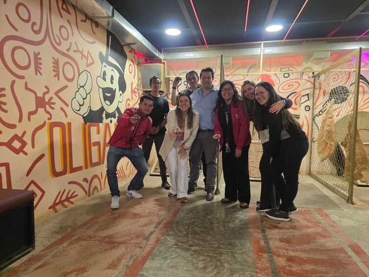 A group of people posing in a room with a cartoon character on the wall and a sign that reads 'OLIGIA.' 5