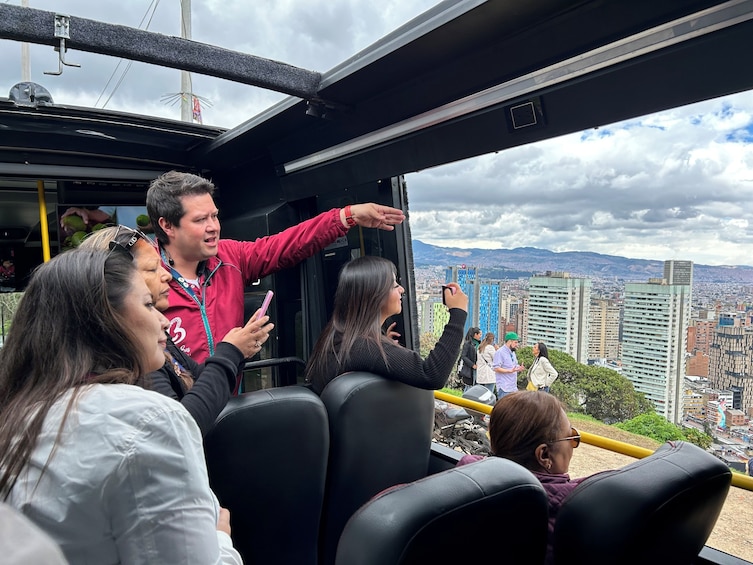 Passengers on a cable car overlooking a cityscape with buildings and mountains. 1