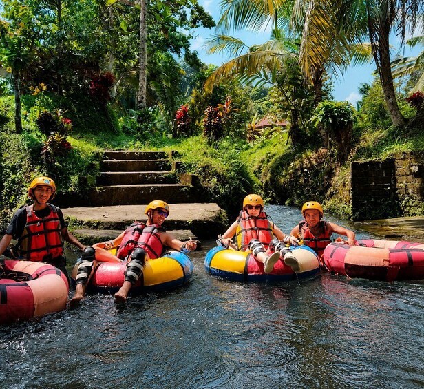 Three people in inflatable rafts on a river surrounded by tropical vegetation. 3