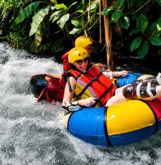 Two people rafting on a river surrounded by dense foliage. 2