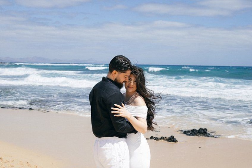 A couple embracing on a beach with waves in the background. 1