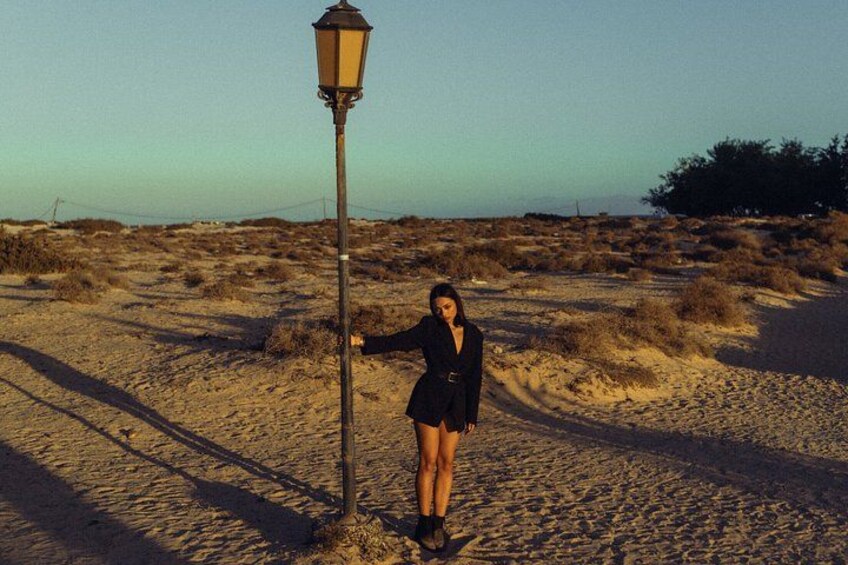 A person standing next to a street lamp in a desert landscape. 3