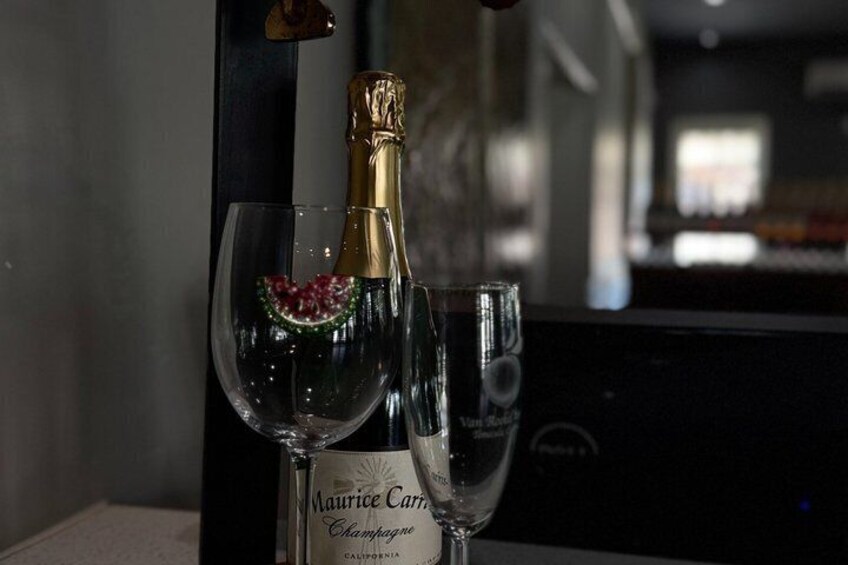 A bottle of Maurice Carre champagne and two glasses on a table. 4