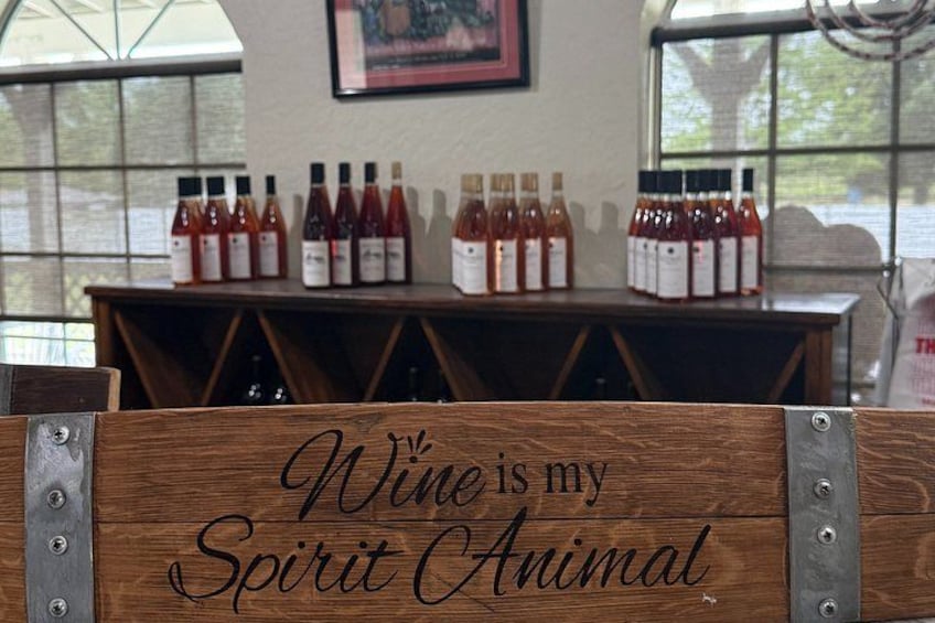 A wooden sign with the text 'Wine is my Spirit Animal' in a rustic setting with bottles of wine in the background. 4