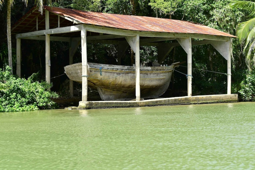 A boat under a covered structure by a body of water. 2