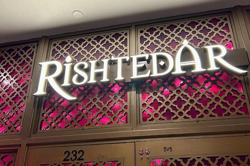 A building facade with a sign that reads 'Rîshtedâr' and the number '232' below it. 2