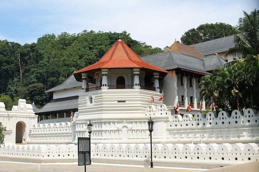 A white temple with a red roof, surrounded by a white fence and palm trees. 1