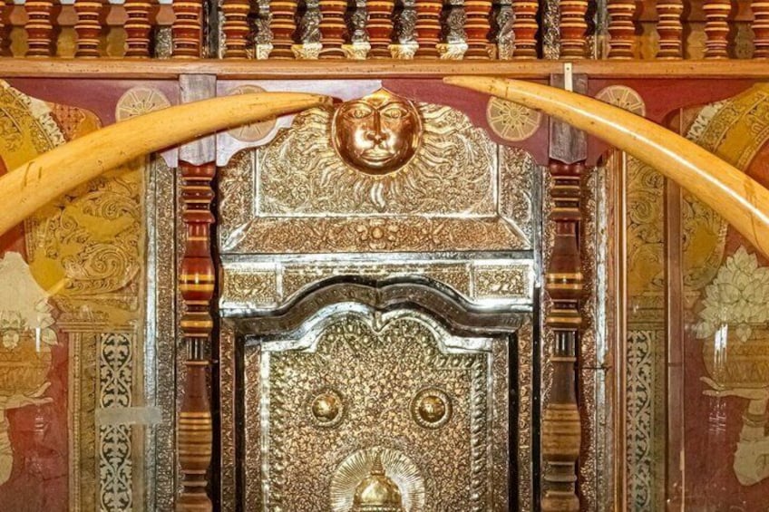 Une porte richement décorée, aux motifs complexes, ornée d’une tête de lion et flanquée de deux poignées en bois courbé. 2