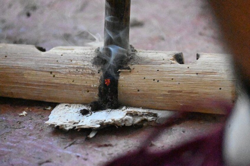 A wooden log with smoke rising from a hole, surrounded by sawdust. 2