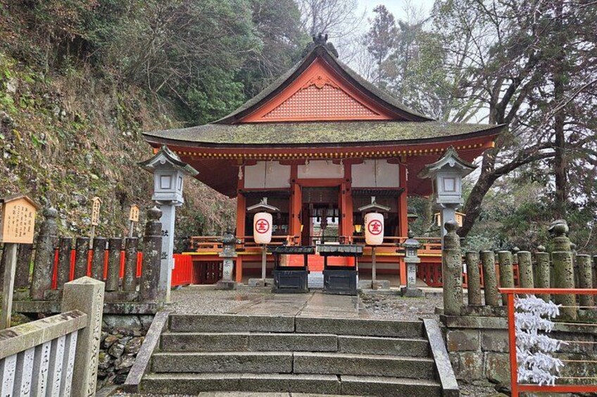 A traditional Japanese temple with a red roof, stone steps leading up to it, and a wooden fence with red barriers. 3