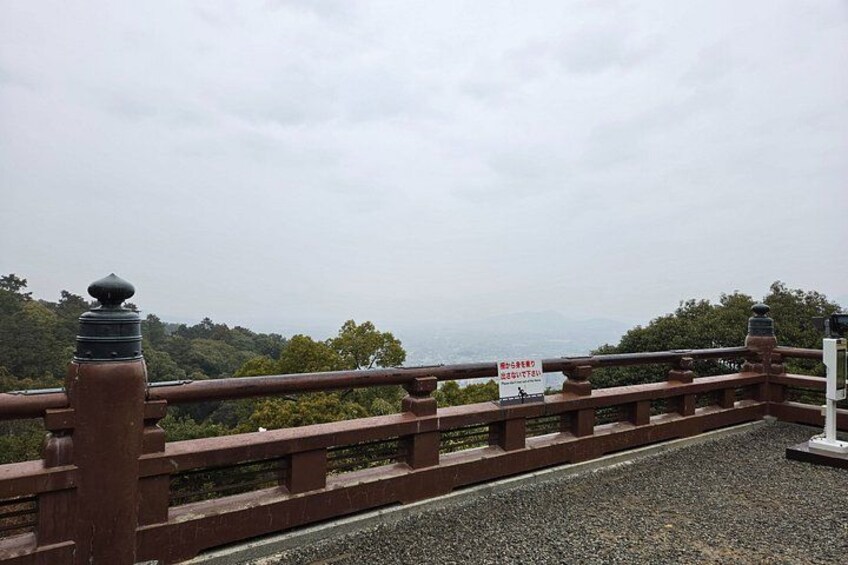 A bridge with a sign, a railing, and a view of the landscape. 4