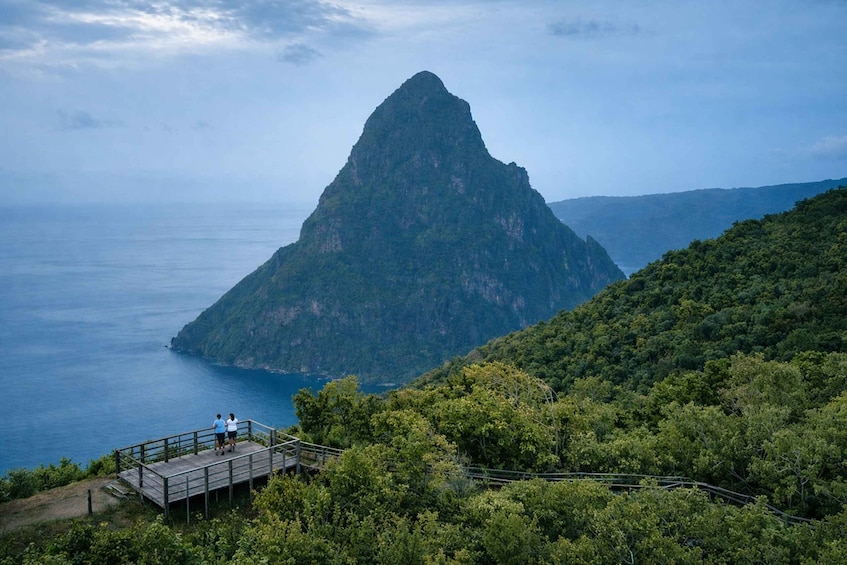 A mountain peak overlooking a body of water, surrounded by dense greenery. 3