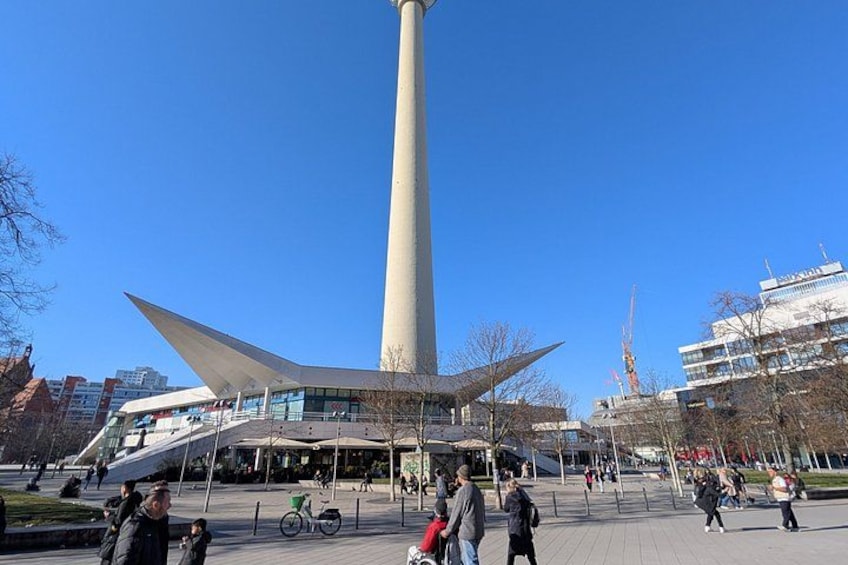 Un bâtiment moderne doté d’une haute tour étroite, d’une place où l’on voit des gens se promener et d’un vélo. 5