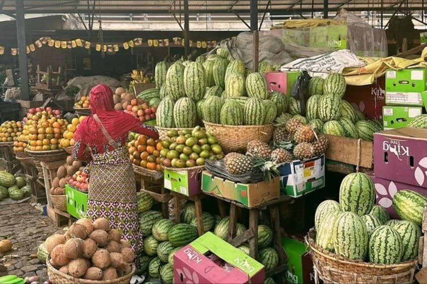 Een markt met verschillende soorten fruit, zoals watermeloenen, ananassen en kokosnoten, gepresenteerd in manden en dozen. 3