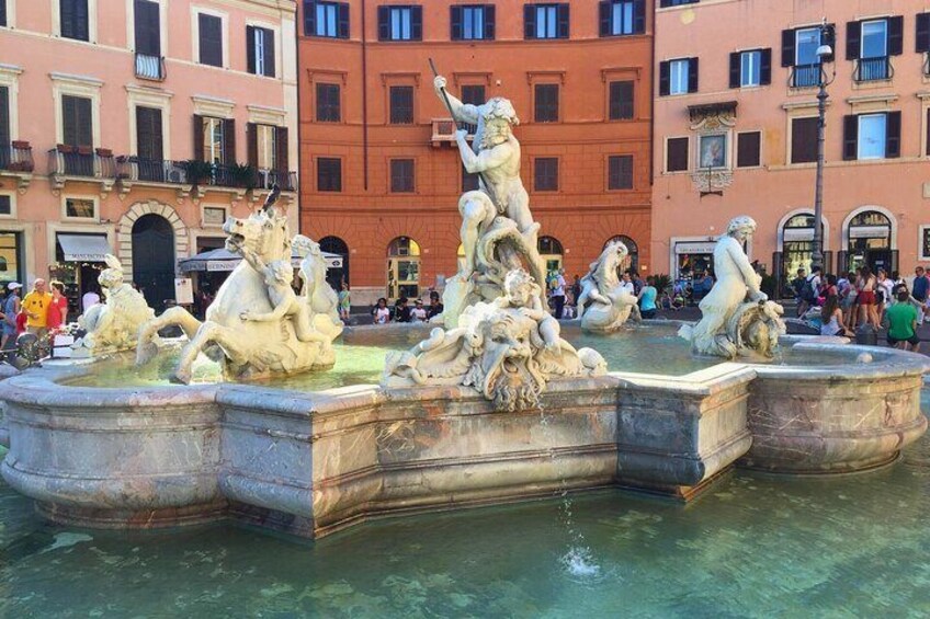 A classical fountain with multiple statues, surrounded by historic buildings. 2