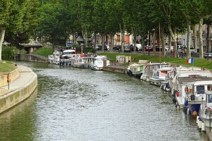 A canal with boats docked along the banks, surrounded by trees and buildings. 3
