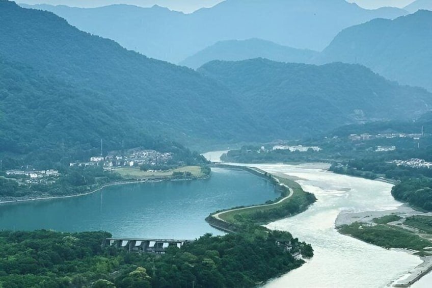 A river winding through a valley with a dam and a small settlement. 1