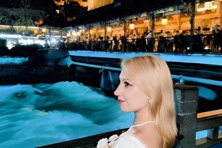 A person seated by a water feature with a restaurant in the background. 5