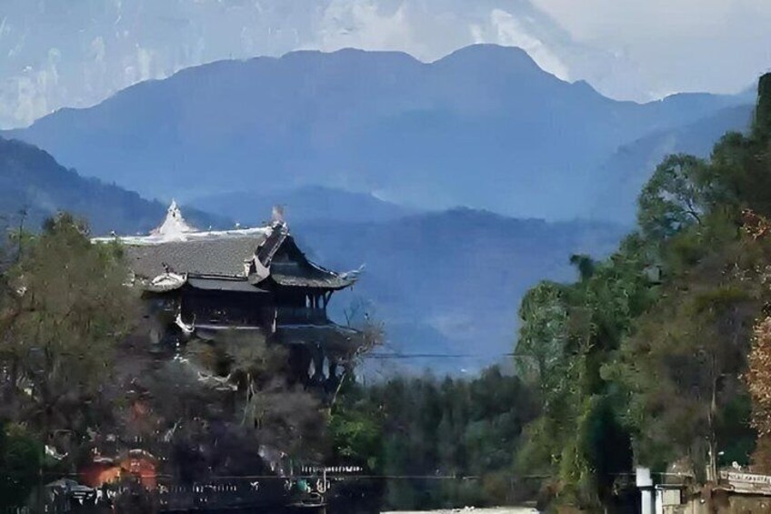 A traditional building with a curved roof, surrounded by trees and mountains in the background. 4