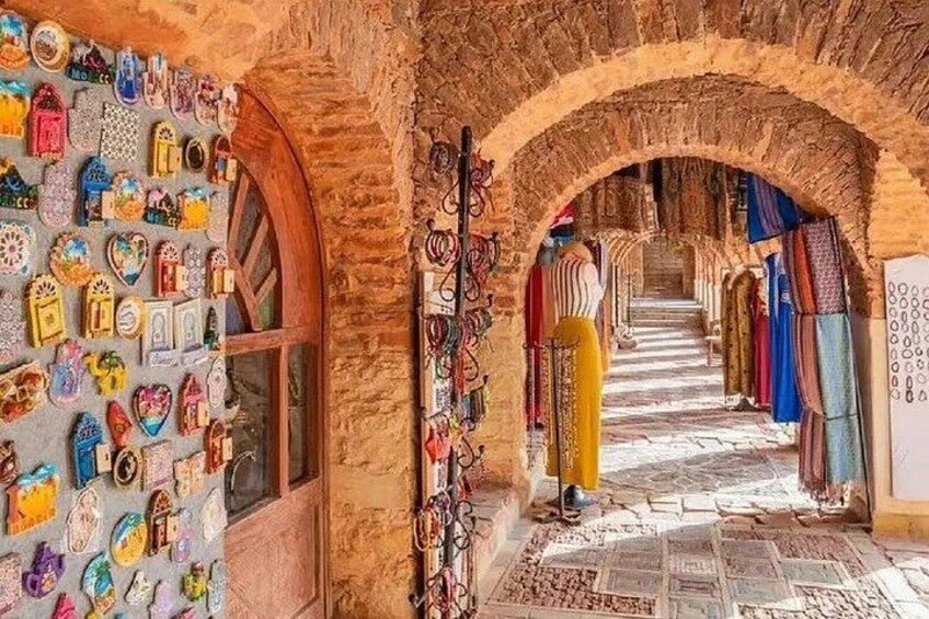 A narrow alley with colorful wall decorations and hanging fabrics. 3