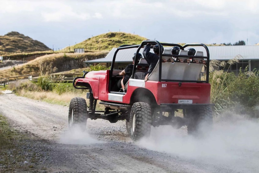 A red off-road vehicle driving on a dirt road with a person climbing out of the back. 5
