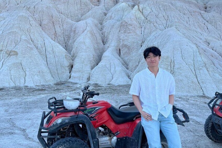 A person standing next to a red ATV in a rocky terrain. 5