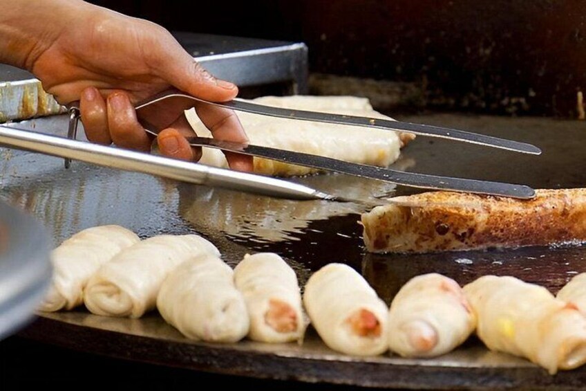 En person som använder en tång för att hantera mat på en grill. 1