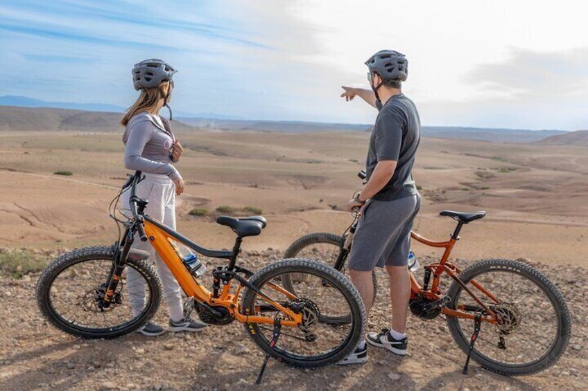 Deux personnes se tiennent sur un chemin de terre, à côté de leurs vélos, et contemplent un paysage désolé. 5