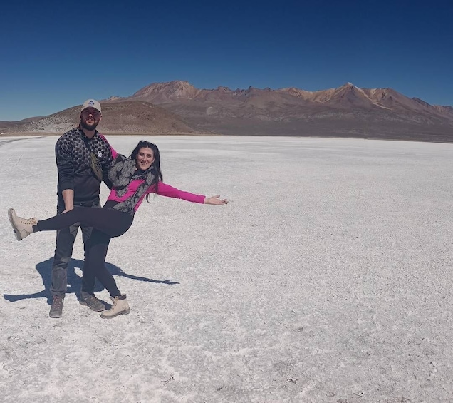 Two people in a vast salt flat with mountains in the background. 4