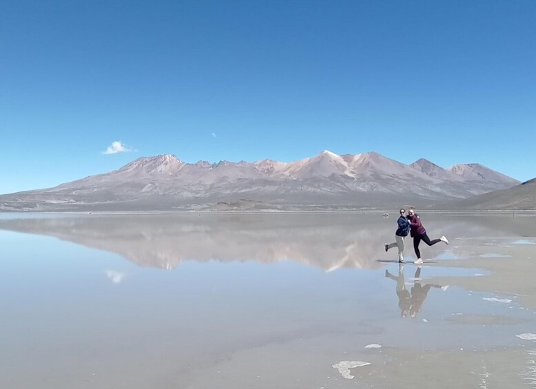 A person running on a reflective salt flat with mountains in the background. 5