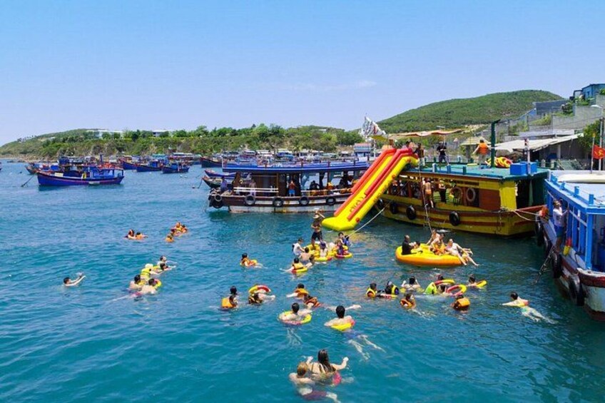 A water park with inflatable rafts, a water slide, and boats. 2