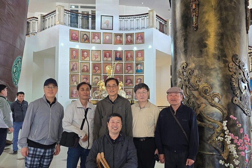A group of people in a building with a large statue and a wall of framed pictures. 4