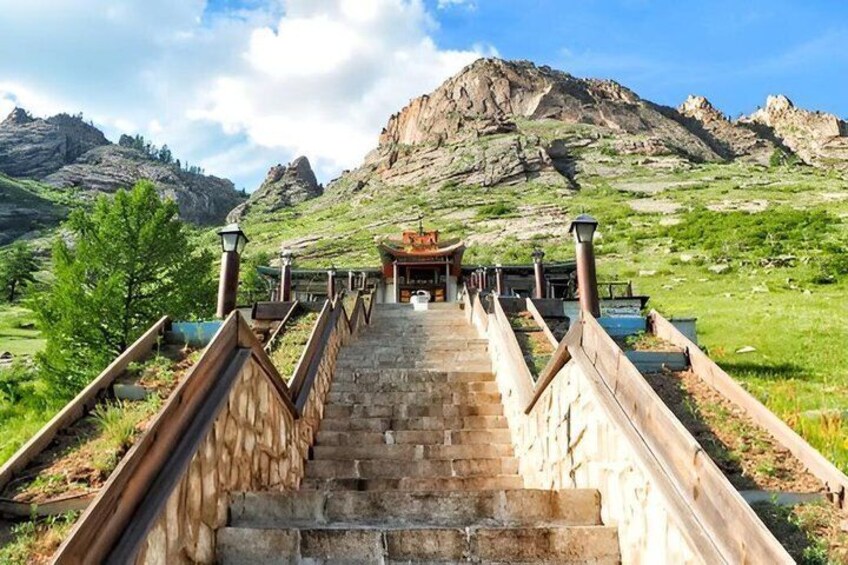 A stone staircase leading to a building with a traditional roof, surrounded by a mountainous landscape. 1