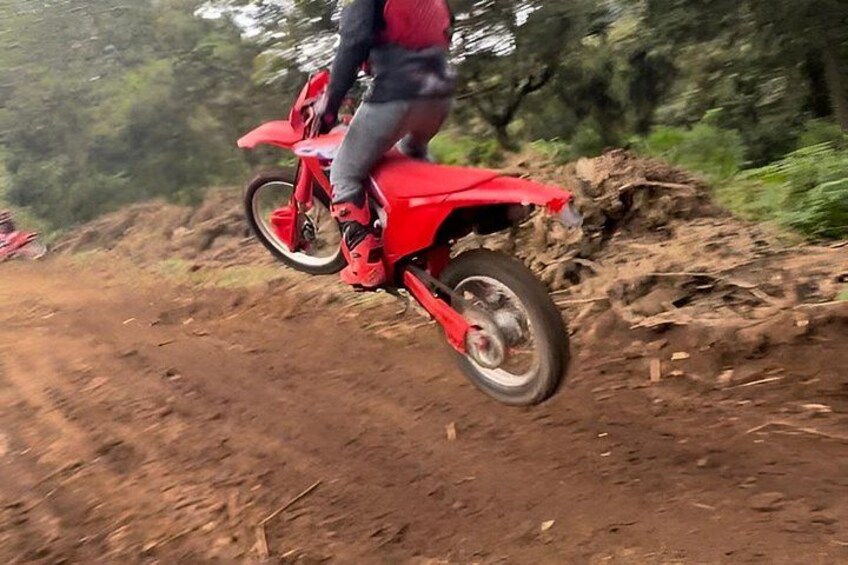 A person riding a red dirt bike on a dirt path. 4