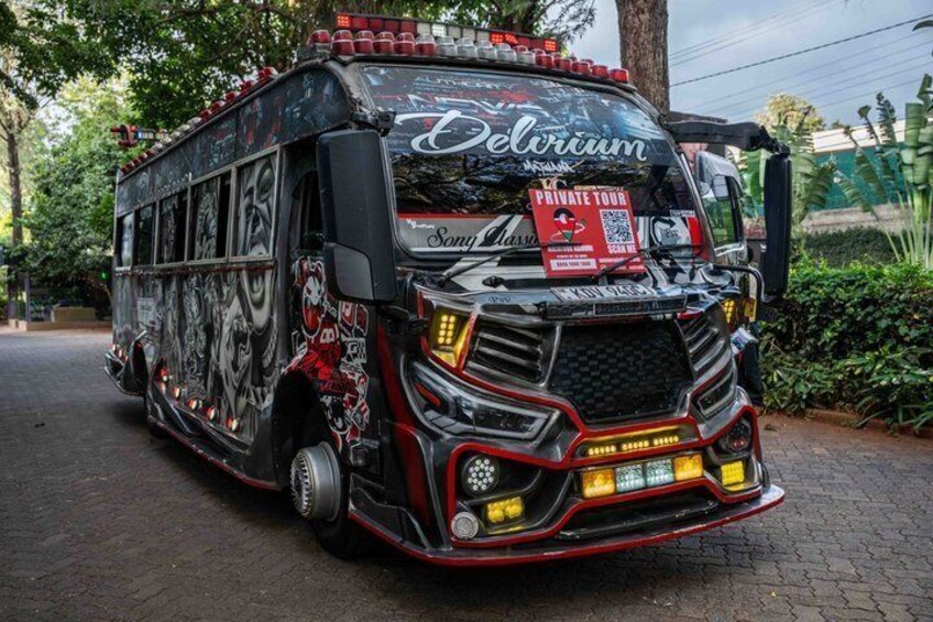 Un autobús grande con la marca 'Delvium' y el texto 'Sonny Classic', estacionado en una carretera pavimentada con follaje al fondo. 3
