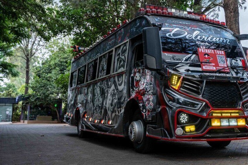 Un autobús con exterior negro y rojo, decorado con diversos gráficos y texto, estacionado en una calle. 2