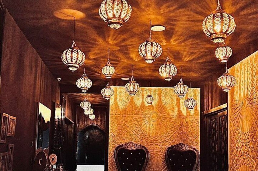 A hallway with ornate chandeliers, patterned wallpaper, and wooden paneling. 2