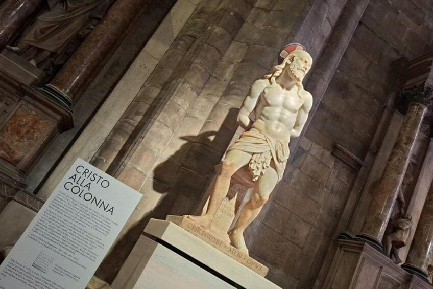 A statue of Cristo alla Colonna in a church with stone columns and a sign. 3