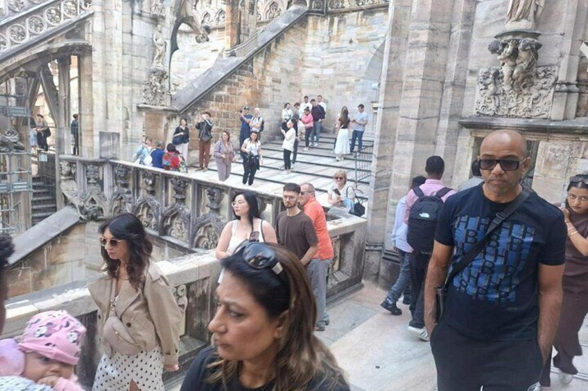 A crowded staircase with ornate stone carvings and a group of people ascending and descending. 5