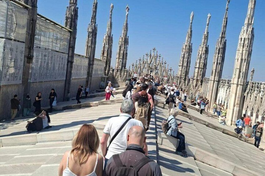 A crowded outdoor area with a long row of tall, ornate columns and a stone wall. 4