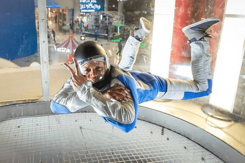 Une personne, vêtue d'une combinaison de parachutisme bleue et blanche, est en plein saut en parachute, et on peut voir son parachute ouvert. 3